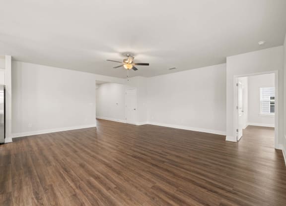 an empty living room with white walls and a ceiling fan
