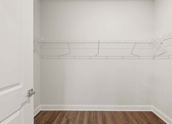 the closet in a bedroom with white walls and a wood floor
