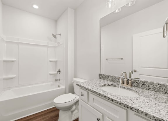 A white bathroom with a toilet, sink, and bathtub.
