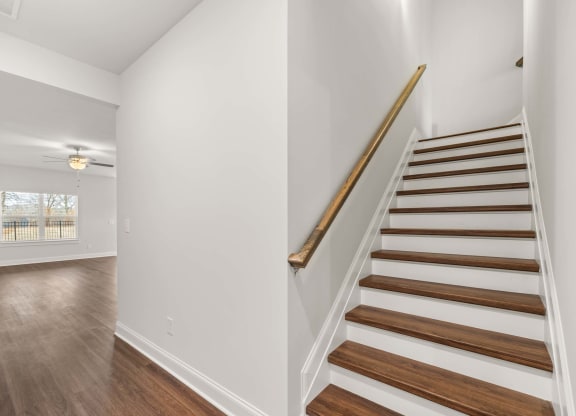 a staircase in a home with white walls and wood floors