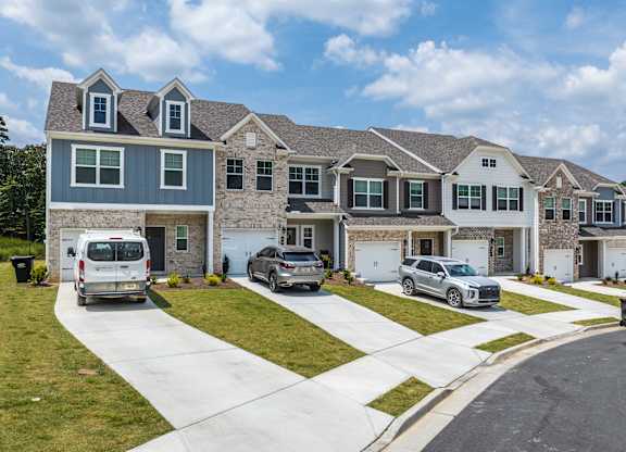 A row of houses with cars parked in front.