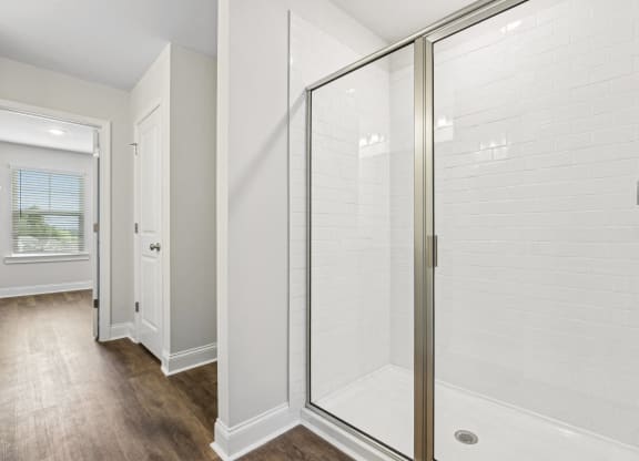 a white shower in a bathroom with a wood floor