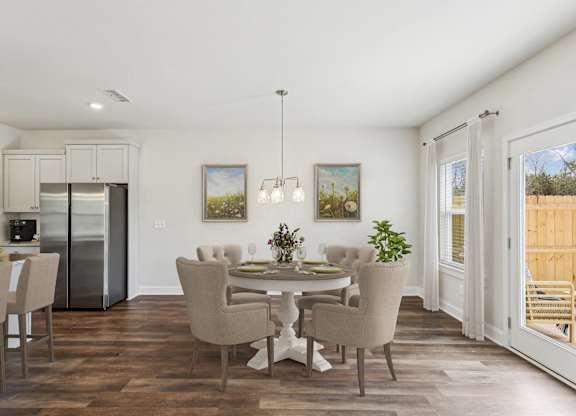 a dining room with a table and chairs and a kitchen with a refrigerator