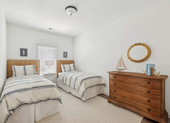 Charming third bedroom featuring two twin beds and a nightstand adorned with a sailboat accent.