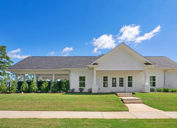 a white house with a green lawn and a blue sky