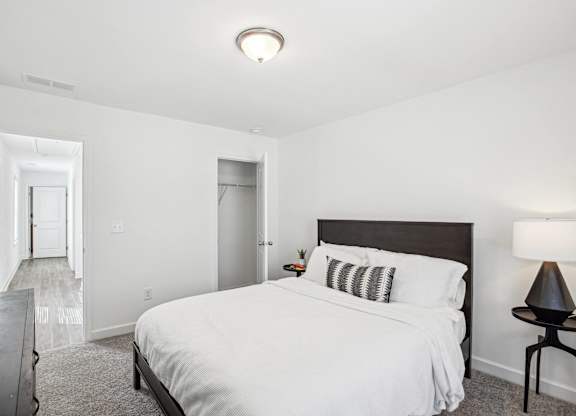 a bedroom with a large white bed and a dark wooden headboard