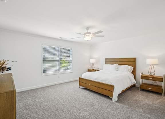 a white bedroom with a bed and a ceiling fan