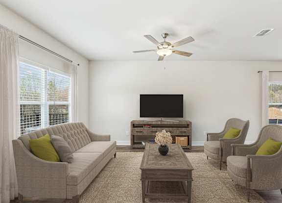 a living room with a couch and chairs and a tv