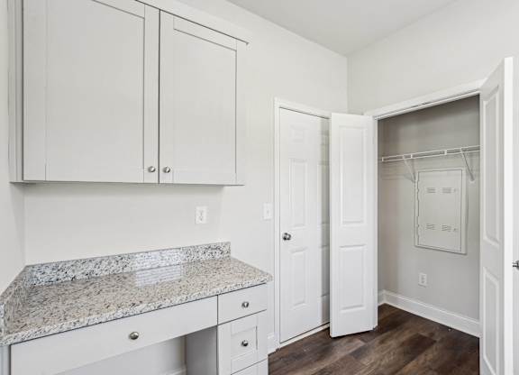 a kitchen with white cabinets and a marble counter top
