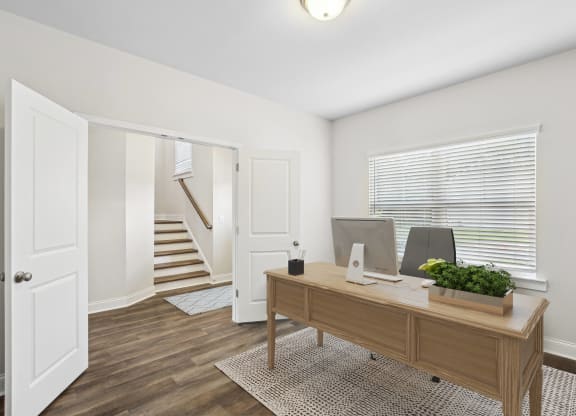 a home office with a wooden desk and a staircase