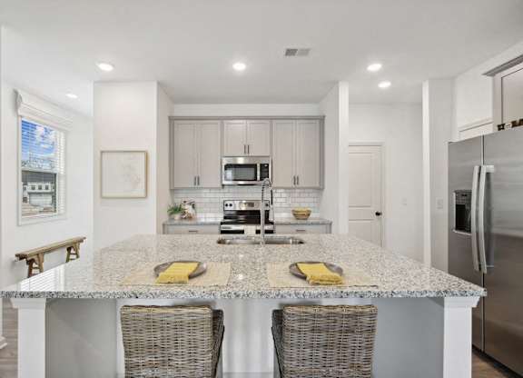 View of the kitchen and entry hallway. Offering bar seating, plenty of cabinet space and granite countertops.