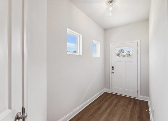The entrance to the Carlisle home featuring rich hardwood-style flooring and crisp white walls.