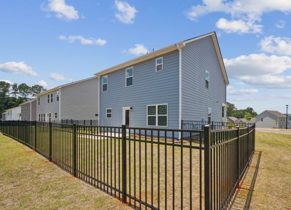 a blue house with a fence in front of a yard