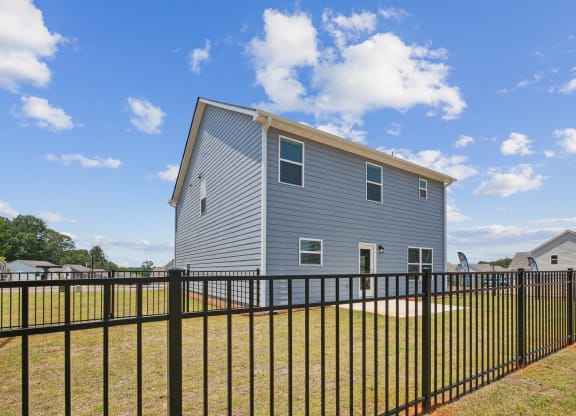the back of a house with a fence in front of it