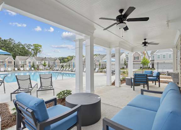 a covered patio with couches and chairs and a pool
