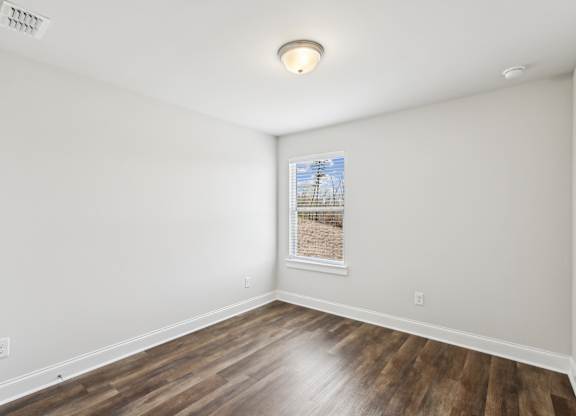 a living room with white walls and wood floors and a window