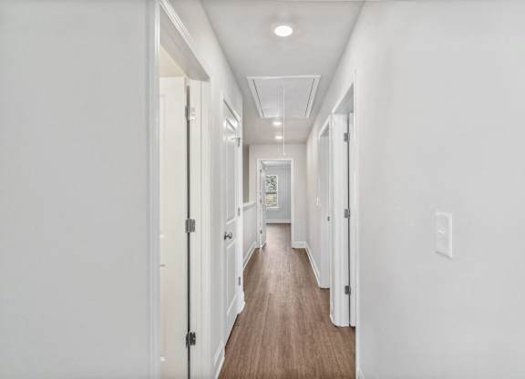 A bright hallway featuring warm wood flooring.