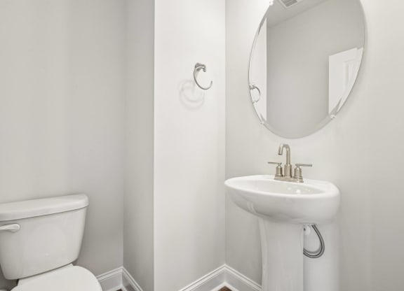a white bathroom with a white toilet and a sink and a mirror