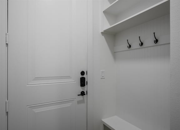 A white door with a black handle and a white bench below it.