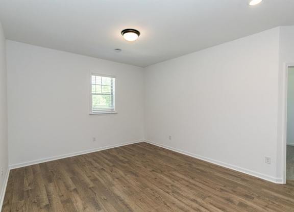 Bedroom with hardwood flooring and windows for natural lighting.