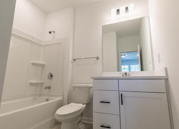 A white bathroom with a toilet, sink, and bathtub.