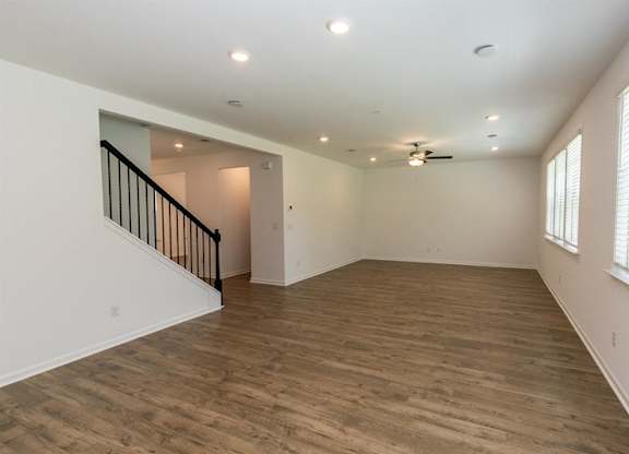 Bright living room featuring wood floors and large windows, perfect for gathering and entertaining.