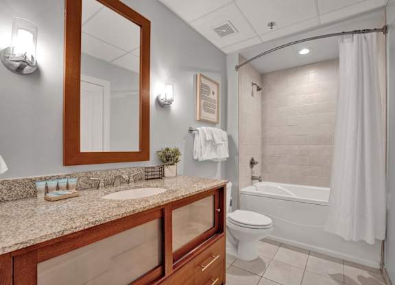 A bathroom with a toilet, sink, and mirror.