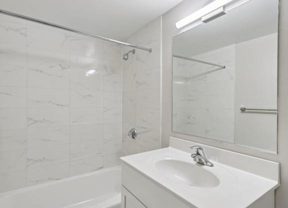 A white sink in a bathroom with a marble tile wall.