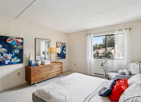 A bedroom with a large bed, a wooden dresser, and a painting on the wall.