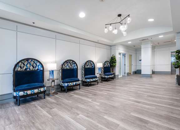 a room with a row of blue chairs and a chandelier