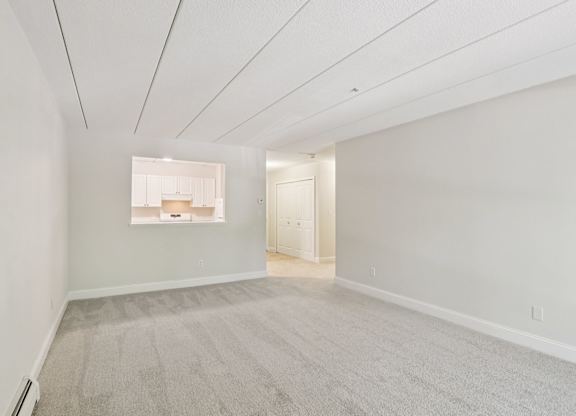 A large empty room with carpeted floor and white walls.