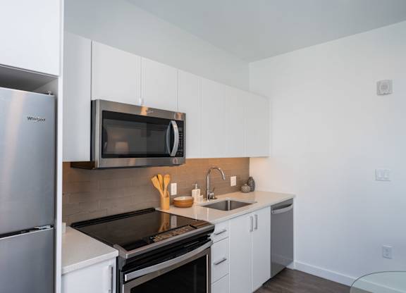 A kitchen with a stainless steel refrigerator and white cabinets.
