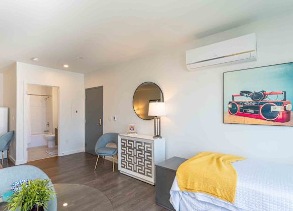 A bedroom with a bed, chair, and a painting on the wall.