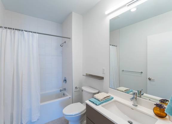 A white bathroom with a toilet, sink, and shower.