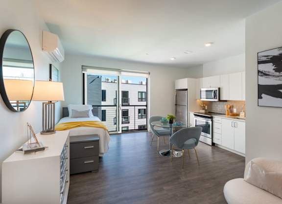 A modern bedroom with a large bed and a small kitchen area.