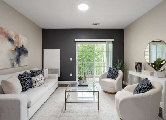 A modern living room with a white sofa, two armchairs, and a glass coffee table.