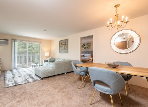 Two bedroom common area living room with balcony and dining space with plush carpeting