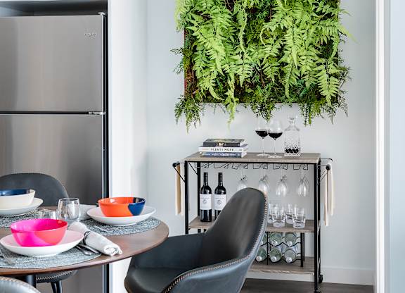 A modern kitchen with a table and chairs and a green plant hanging on the wall.