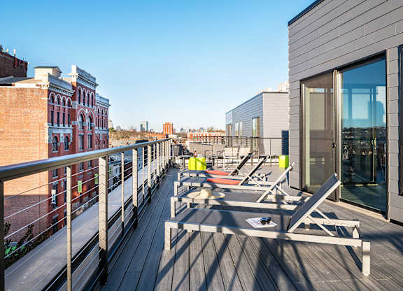 A balcony with chairs and a table is on the roof of a building.