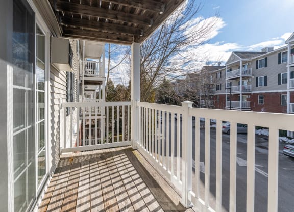 a porch with a white railing and a building in the background