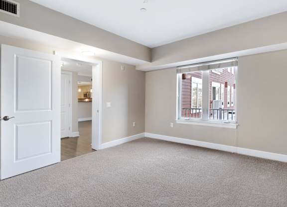 A room with a white door and a window with a view of a building outside.