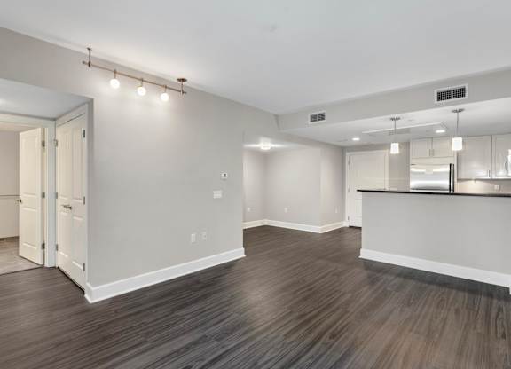A spacious room with wood flooring and a bar area.