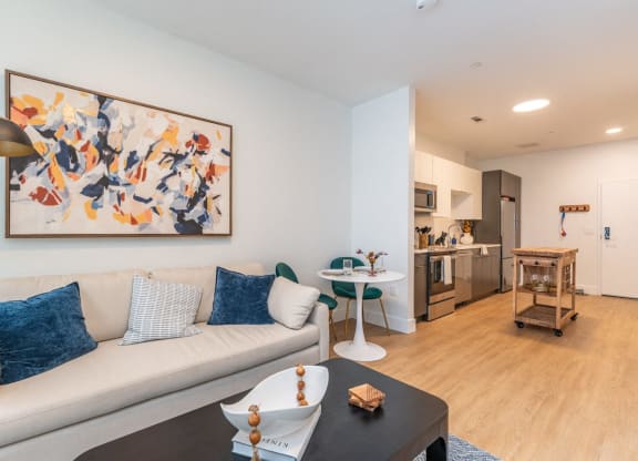 a living room with a couch and a coffee table and a kitchen in the background