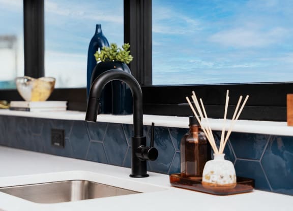 a kitchen sink with a black faucet and a window