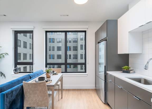 Studio apartment with space for dining, lounge area with stainless appliances and white backsplash