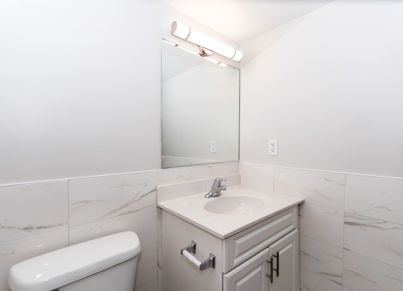 a bathroom with white tiles and a white sink and toilet