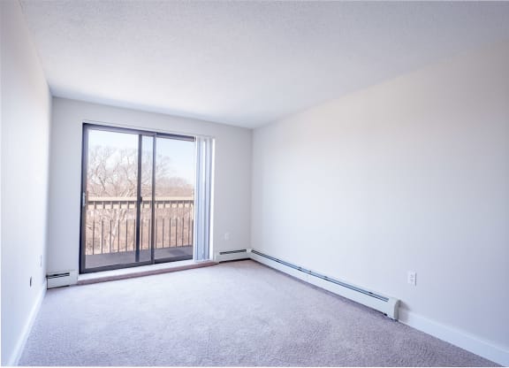 an empty bedroom with a sliding glass door and a balcony