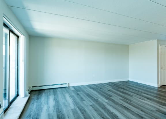 an empty room with a large window and hardwood floors