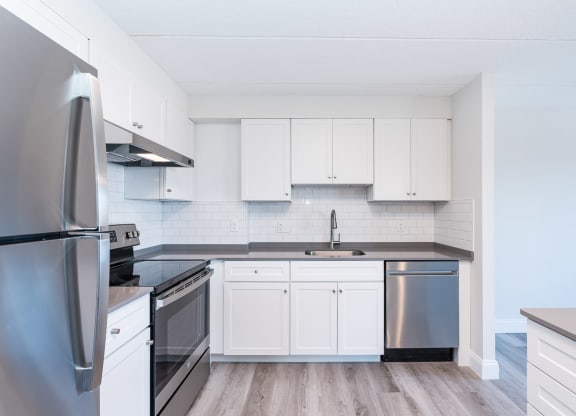 a kitchen with white cabinets and stainless steel appliances
