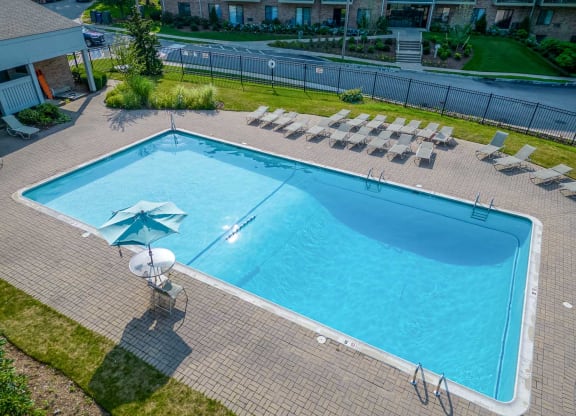 an aerial view of a large swimming pool with lounge chairs and an umbrella
